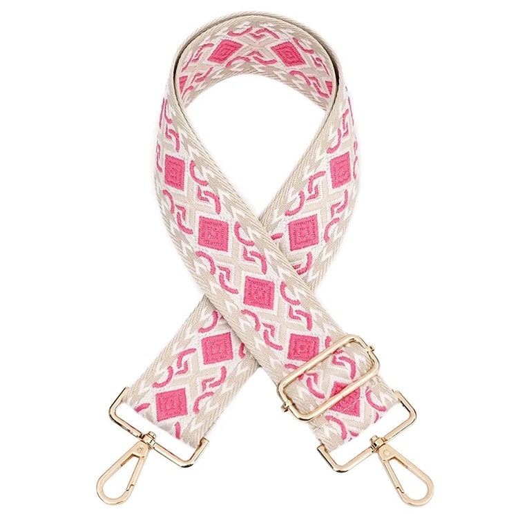 Bild på en bred axelrem till väska med mönster i rosa och beige färger.