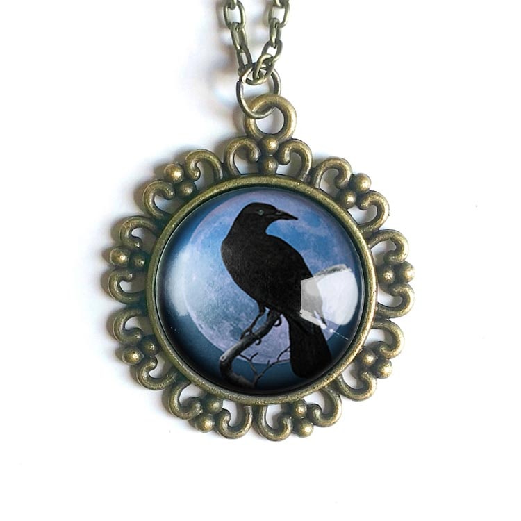 Bild på ett halsband med en berlock med en illustration av en kråkfågel i vintagestil.