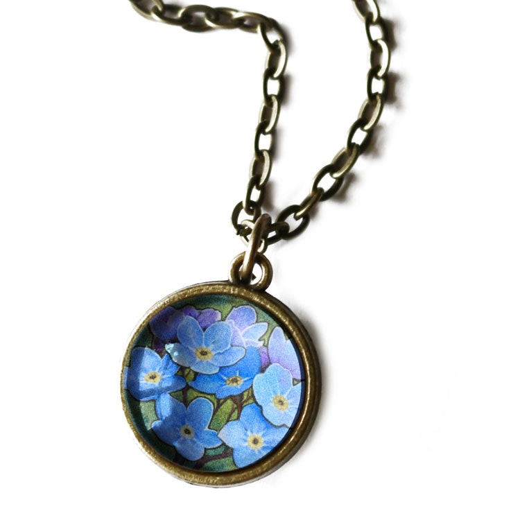 Bild på ett vintageinspirerat halsband i mässing med illustrationer av förgätmigej.