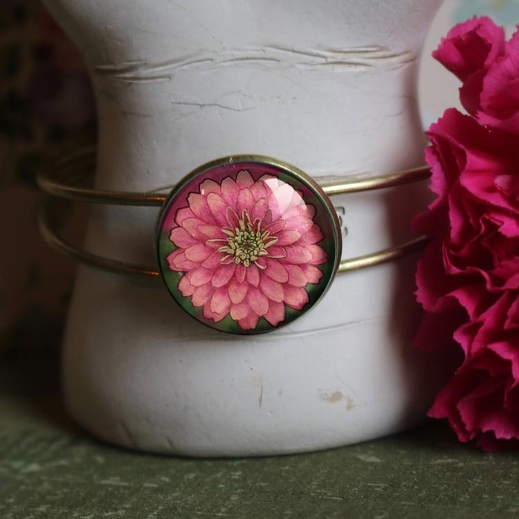 Bild av ett vintageinspirerat stelt armband med en illustration av en rosa zinnia