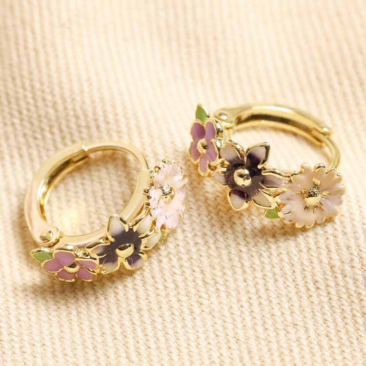 Guldpläterade huggie hoops med emaljblommor i rosa och lila pastellfärger.