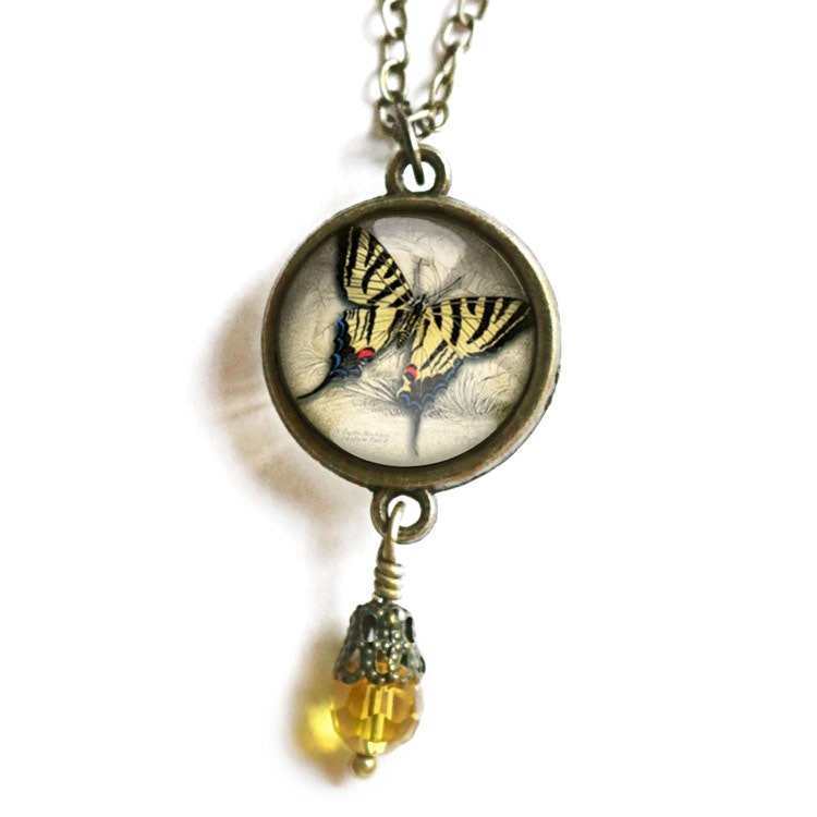Vintageinspirerat halsband med en illustration av en gul fjäril med en pärla undertill.