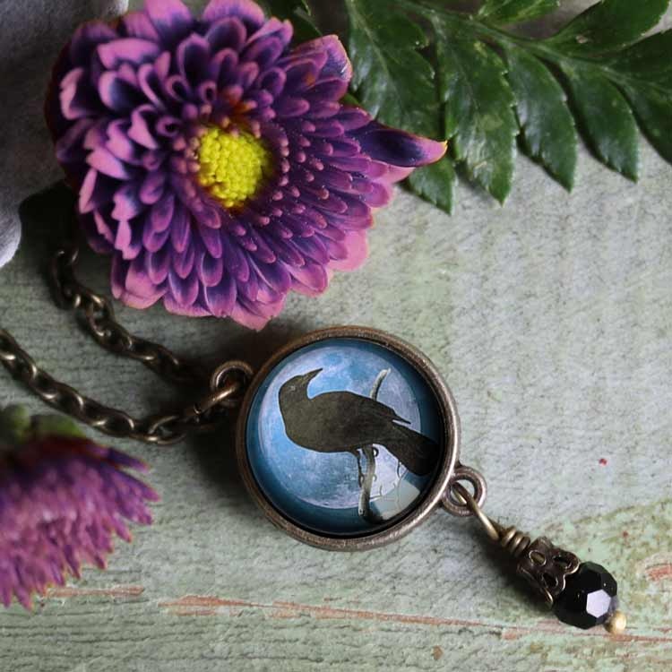 Halsband med en dubbelsidig berlock med en kråkfågel på. Under berlocken hänger en pärla.