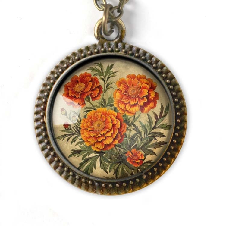 Vintageinspirerat halsband med en illustration av ringblommor i en stor berlock.