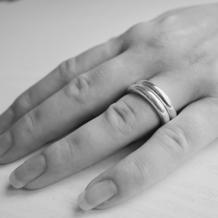 Närbild på hand där två enkla silverringar bärs på samma finger. hand with same two silver rings.