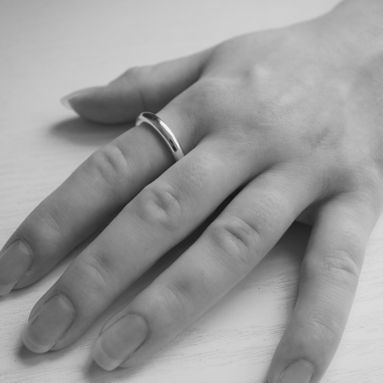 Närbild på hand där en enkel slät silverring. hand with a silver ring.