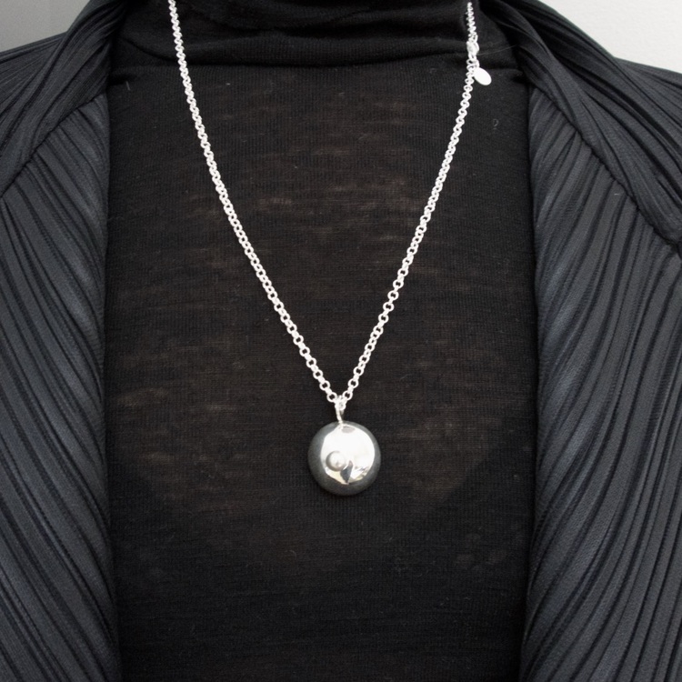 silverhänge i from av ett bröst på lång silverkedja. silver pendant, shape as a breast on a long silver chain.