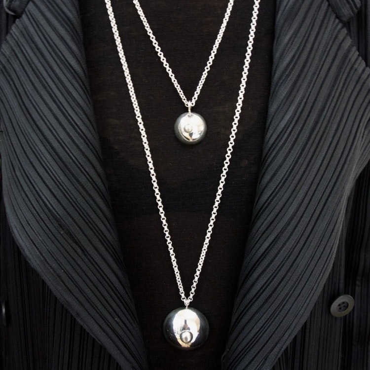 två silverhängen i from av bröst på långa silverkedjor. silver pendants, shape as a breasts on long silver chains.