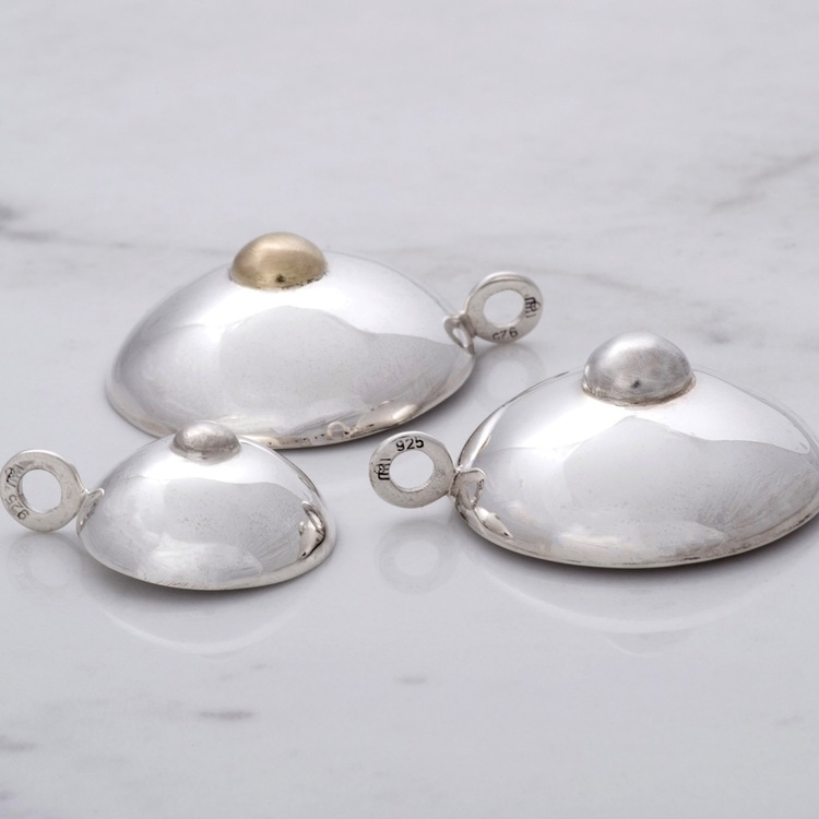 tre silverhängen i form av bröst, detalj i guld. three silver pendants, shape as breast detail with gold.