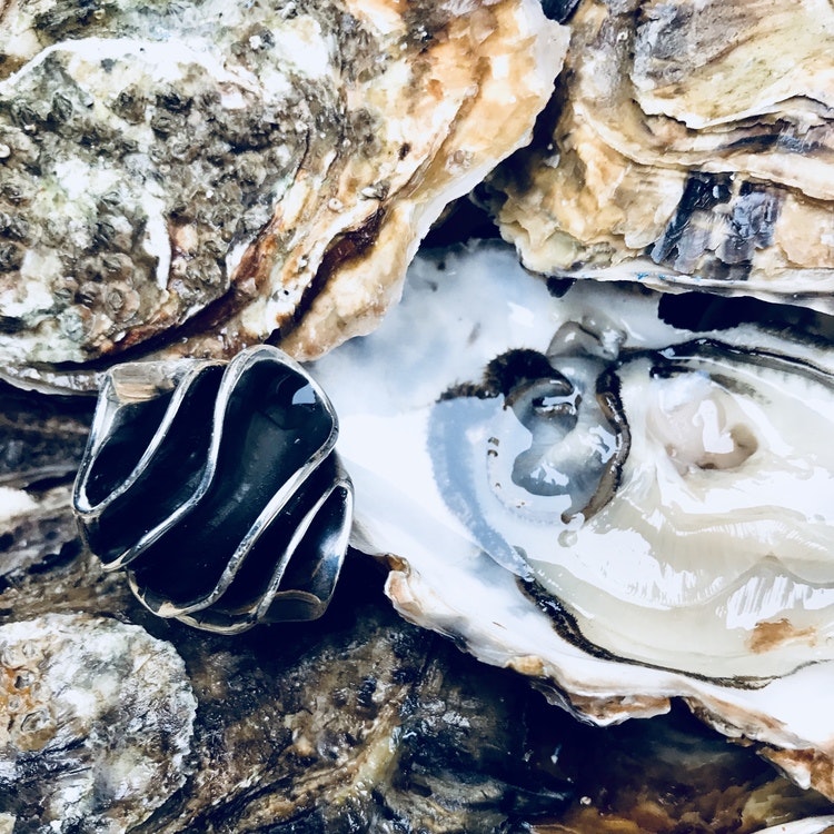 stor massiv oxiderad silverring som ligger bland ostron. big massive oxidised silver ring laying on oysters.