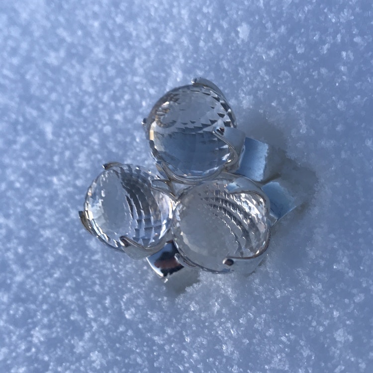 stora silverringar med facettslipade bergskristaller stående i snö. big silver rings with crystal quartz standing in snow
