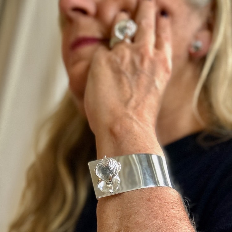 Arm med stort silverarmband och silverring med bergskristall. Hand with big silver bracelet and silverring with crystal quartz.