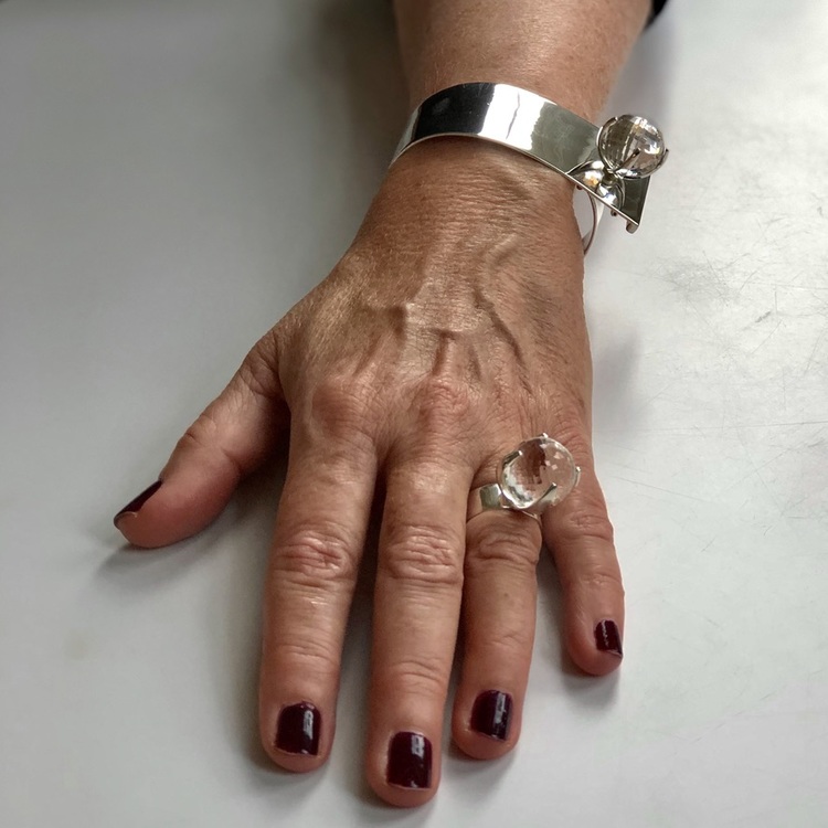 Arm med stort silverarmband och silverring med bergskristall. Hand with big silver bracelet and silverring with crystal quartz.