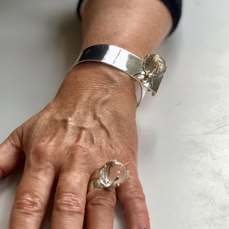 Arm med stort silverarmband och silverring med bergskristall. Hand with big silver bracelet and silverring with crystal quartz.