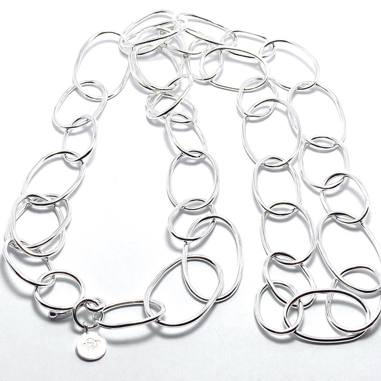långt silverhalsband med runda länkar i olika storlekar. long silver chain with round links in various sizes.