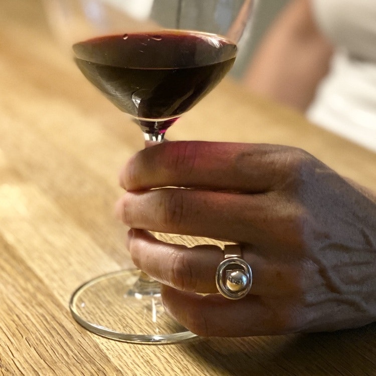 Hand med stor silverring och ett glas vin