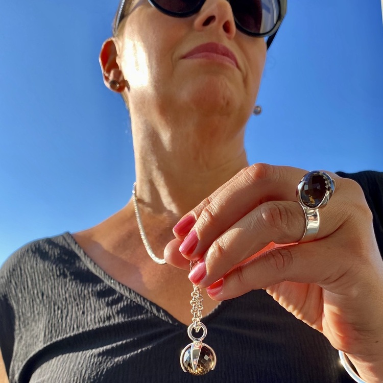 Kvinna med matchande armband, hänge, ring och örhängen med rökkvarts. Woman with matching earrings, ring, pendant and bracelet with smokey quartz