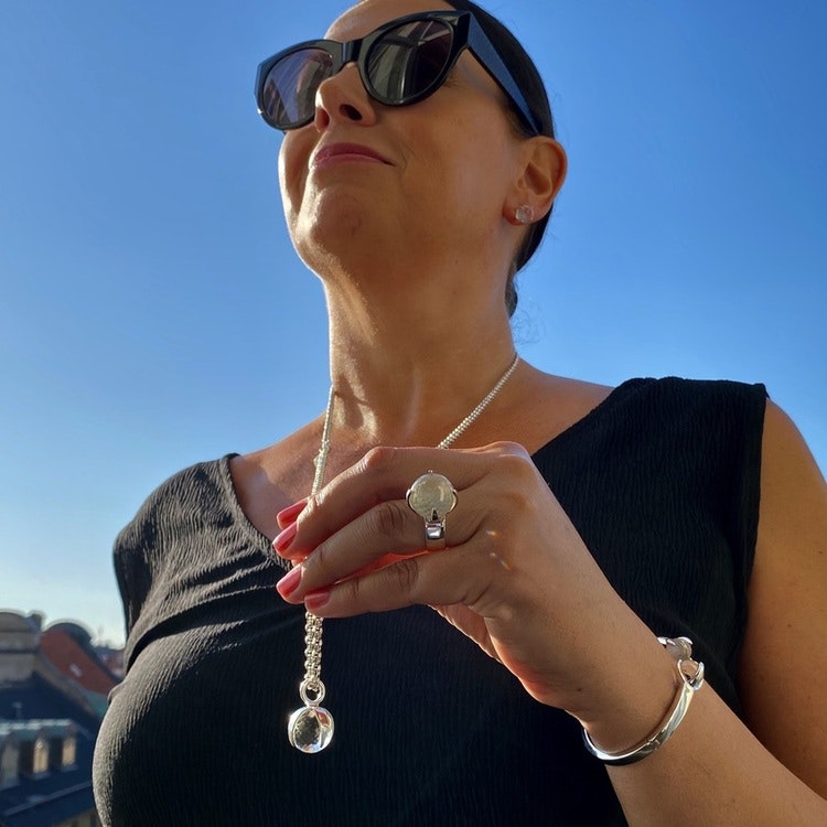 Kvinna med matchande armband, hänge, ring och örhängen med bergskristall. Woman with matching earrings, ring, pendant and bracelet with crystal quartz