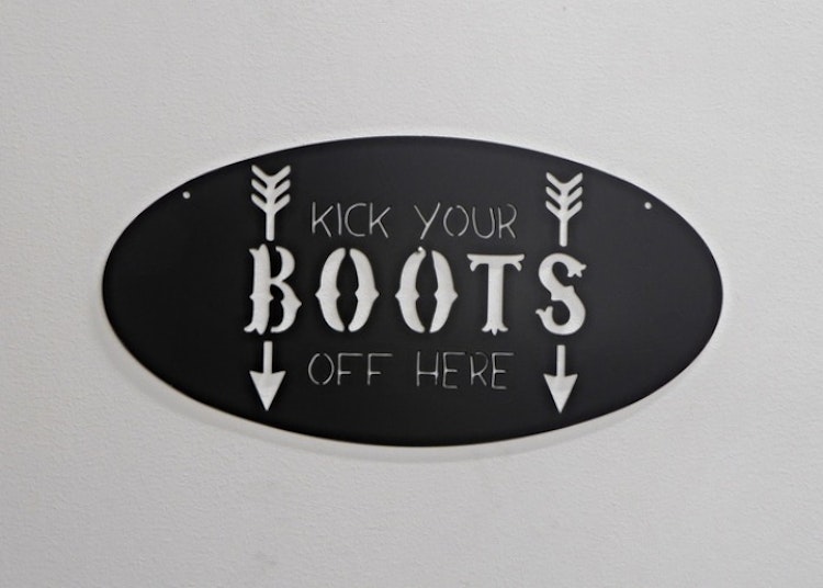 Oval skylt med texten "kick your BOOTS off here".