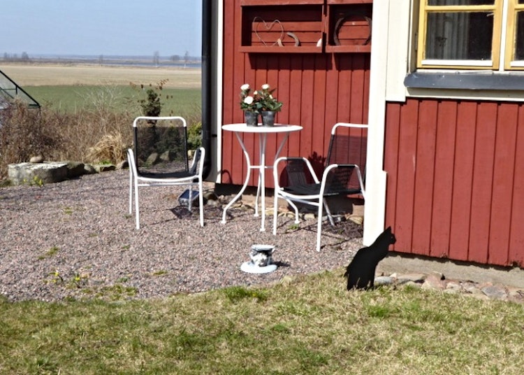 Sittande svart katt i plåt som är nedstucken i marken.