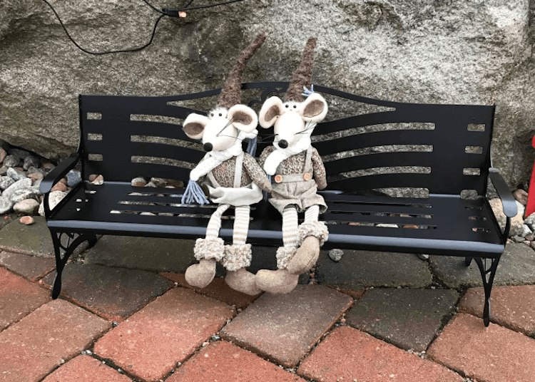 Två gosedjur sittandes på en liten parkbänk i plåt.