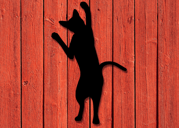 Svart kattsiluett i plåt mot röd husfasad.