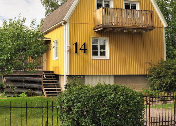Svarta fasadsiffror på gult hus.