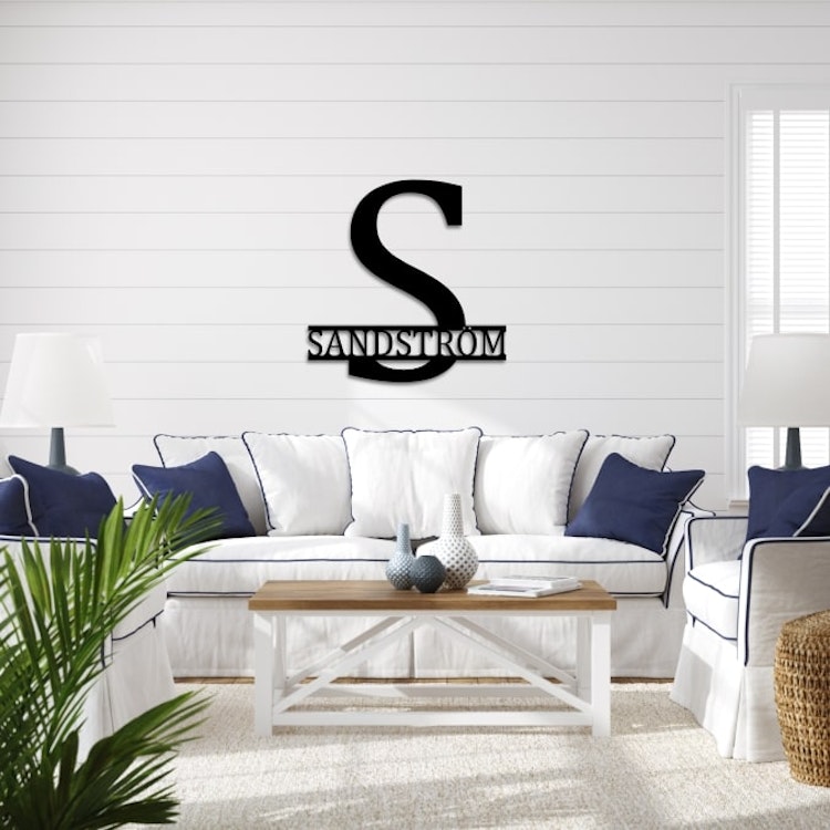 Stilrent monogram på vit vägg, med namnet Sandström.