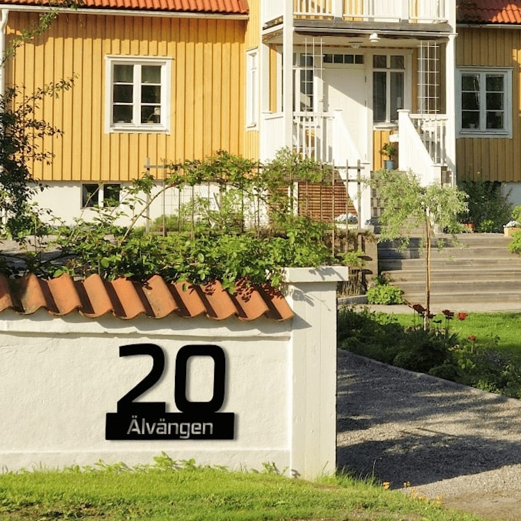 Husnummerskylt monterad på stenmur.