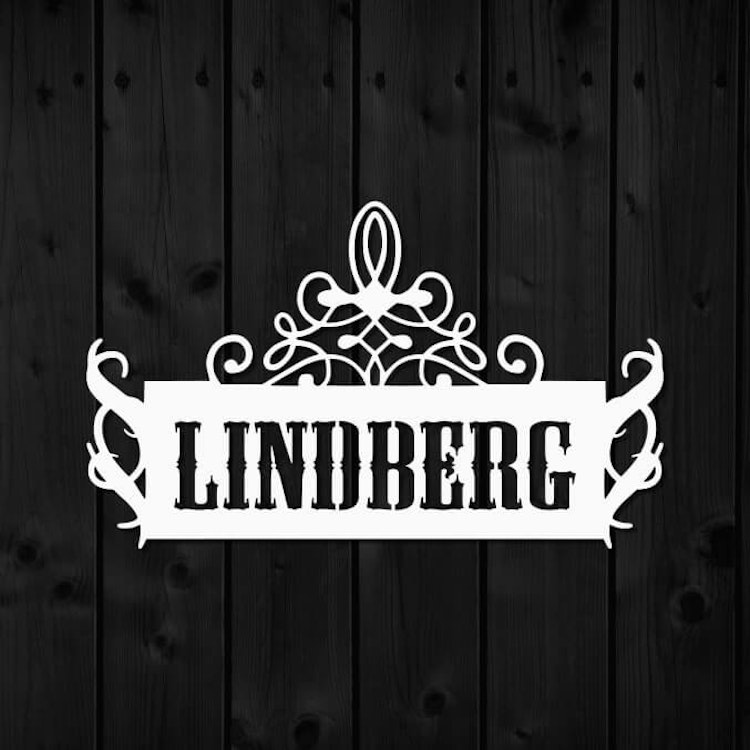 Vitlackerad väggdekor i stål, med namnet LINDBERG utskuret.