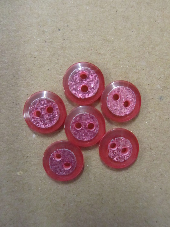 Rosa knapp med glitter. Två hål. Storlek 12 mm.