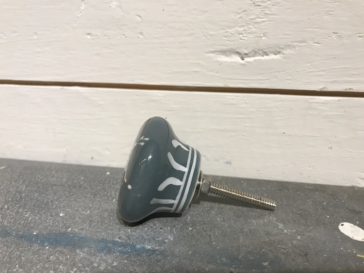 Blå keramikknopp med vita mönster.