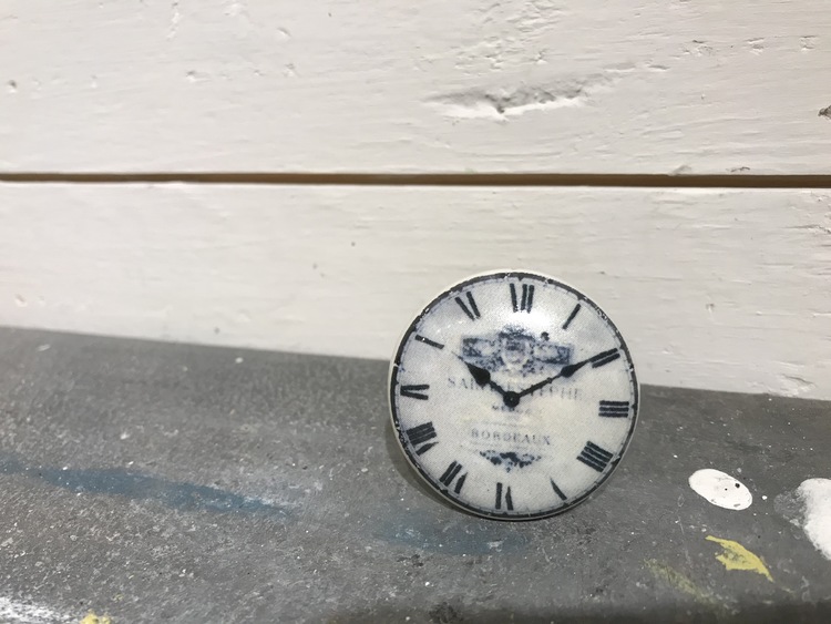 Vit keramikknopp med klocka på framsidan.