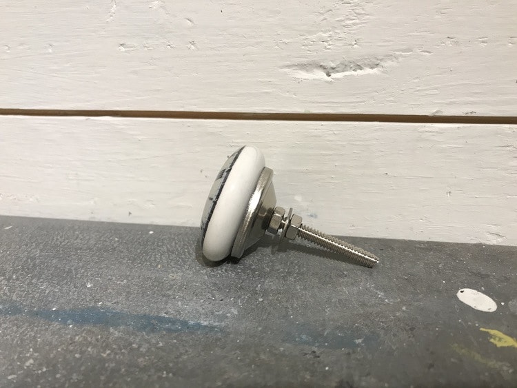 Vit keramikknopp med klocka på framsidan.