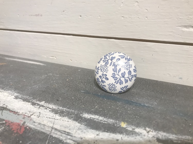 Vit knopp i keramik med blå blommönster.
