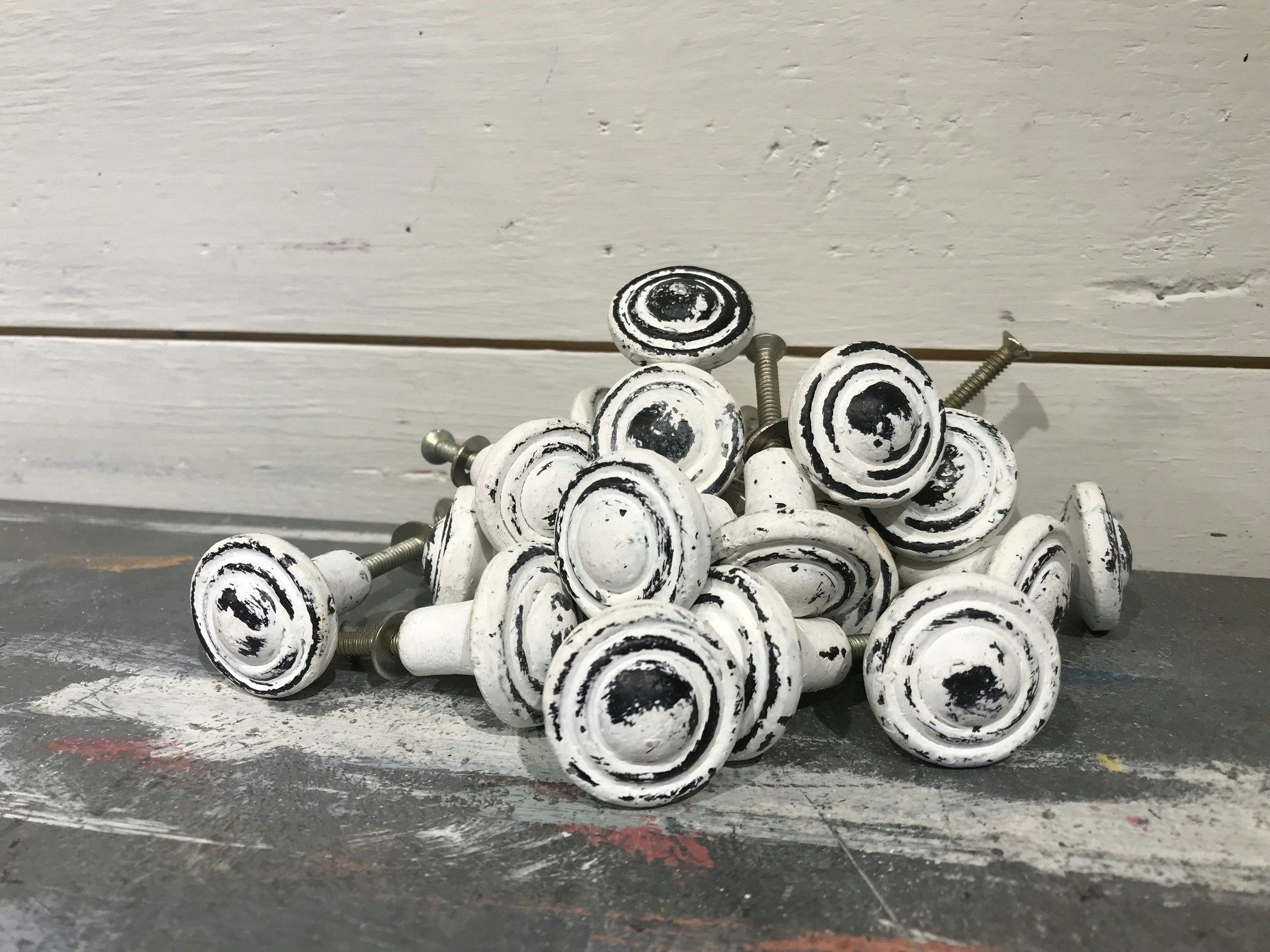 Knopp i metall, vit med slitningar i svart