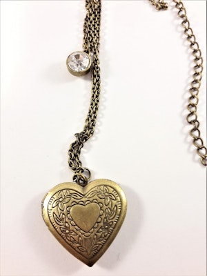 Vacker guldfärgad medaljong i kedja med glittrande sten och öppningsbart hjärta med plats för foto