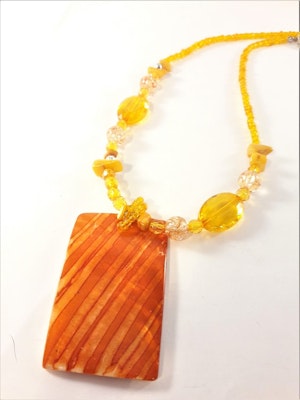 Halsband med orange detaljer och snäckskal