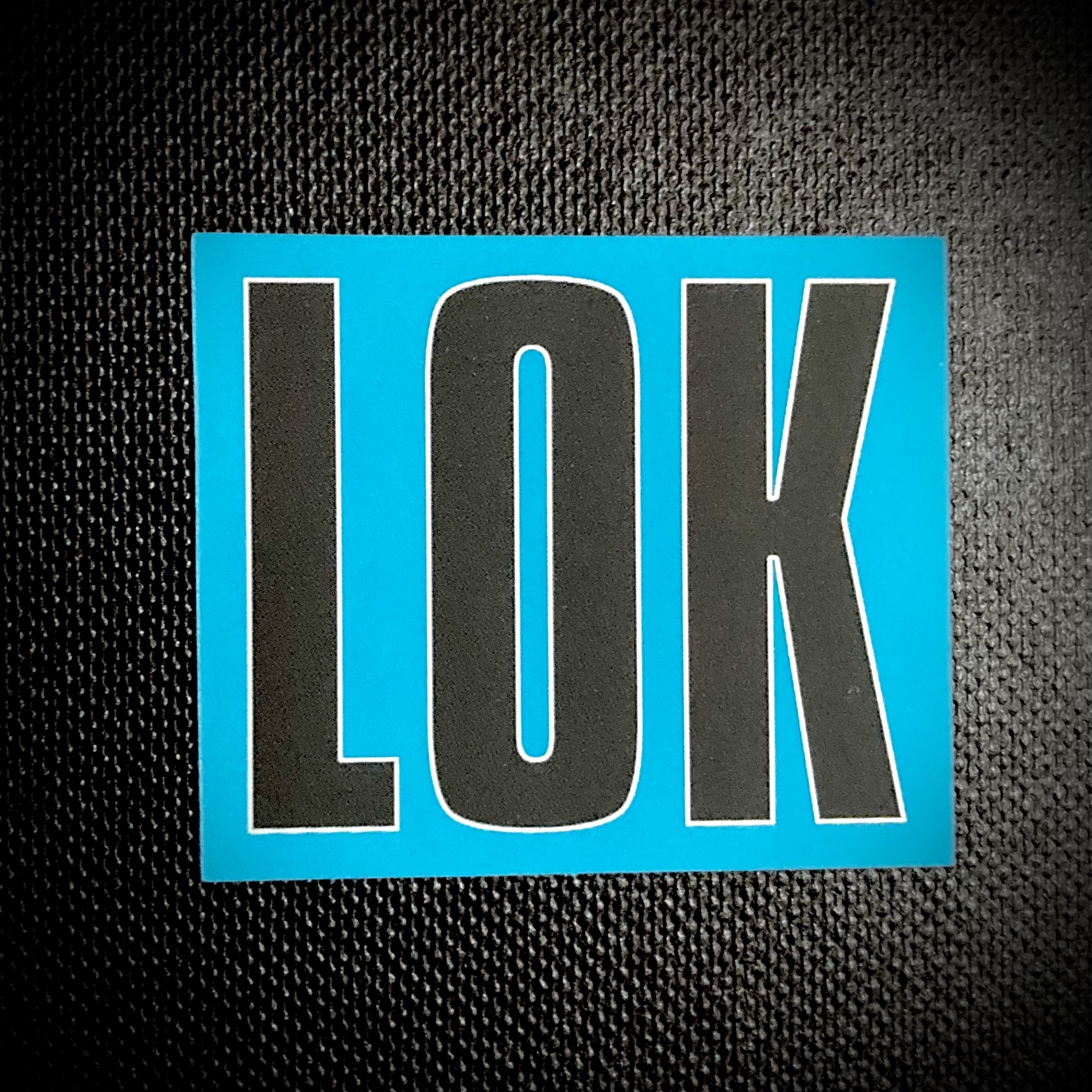 Klistermärke | LOK-loggan" (Svart logo + Silver Outlined / Turkos-Blå Bakgrund)