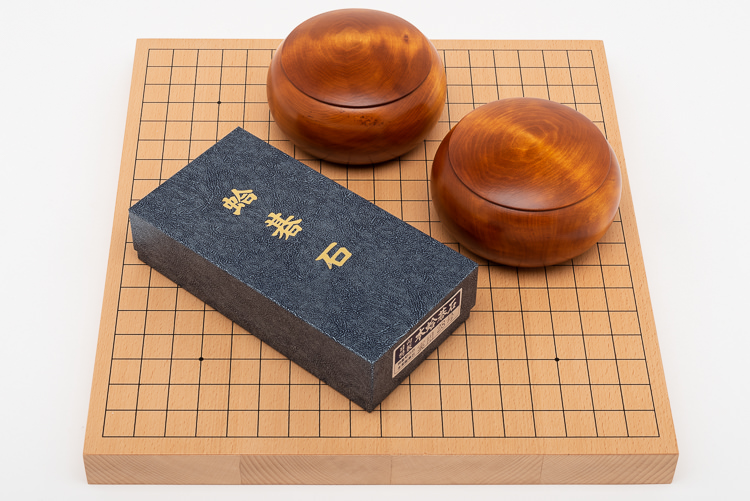 Traditionellt Go-spel med stenar i snäckskal och skiffer, tjockt bräde i bokfanér och träskålar