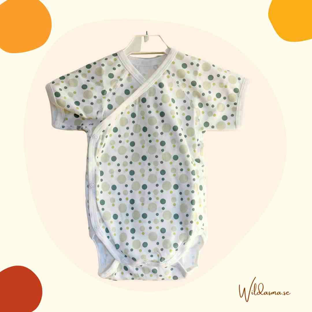 Babykläder kortärmad body vit med gröna prickar.