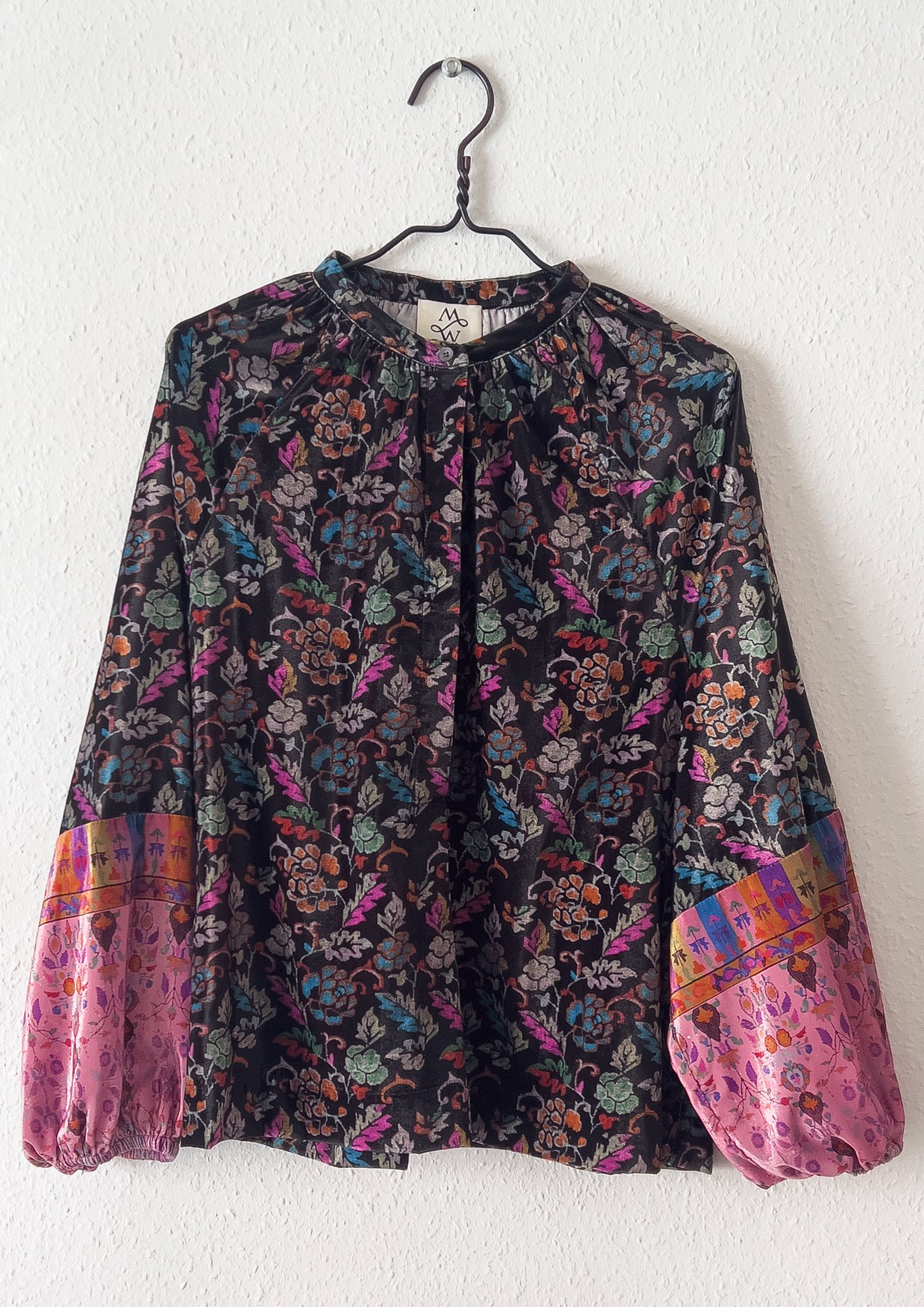 Svart blus med rosa ärmar i mjuk tunn velour, med vackert print. Puffärm och knappar framtill. M Wiesneck