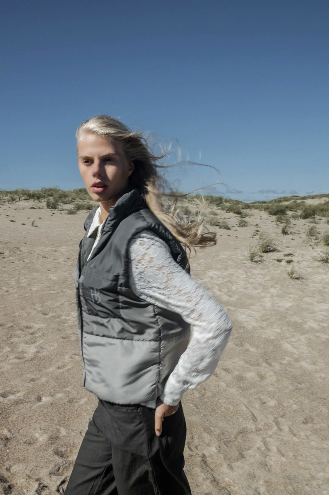 Sportig väst i lätt material med foder, tre gröna toner och tryck i reflex baktill. Från Humble by Sofie