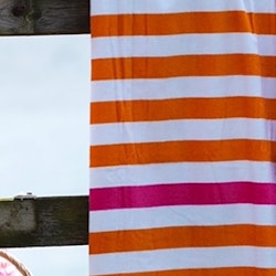 Athena ett randigt frottébadlakan i vitt, orange och en rosa rand i 100% bomull från Noble house, mått 90 x 150 cm.