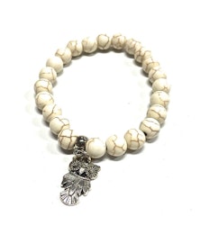Armband med pärlor och en uggleberlock i polystone med elastiskt band. Art.nr: H 02008. Färg: Off-white.