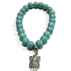Armband med pärlor och en uggleberlock i polystone med elastiskt band. Art.nr: H 02008. Färg: Aqua.