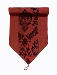 Oriental en röd bordlöpare i orientalisk stil med medaljongmönster i blanka textilier, mått 40 x 140 cm.