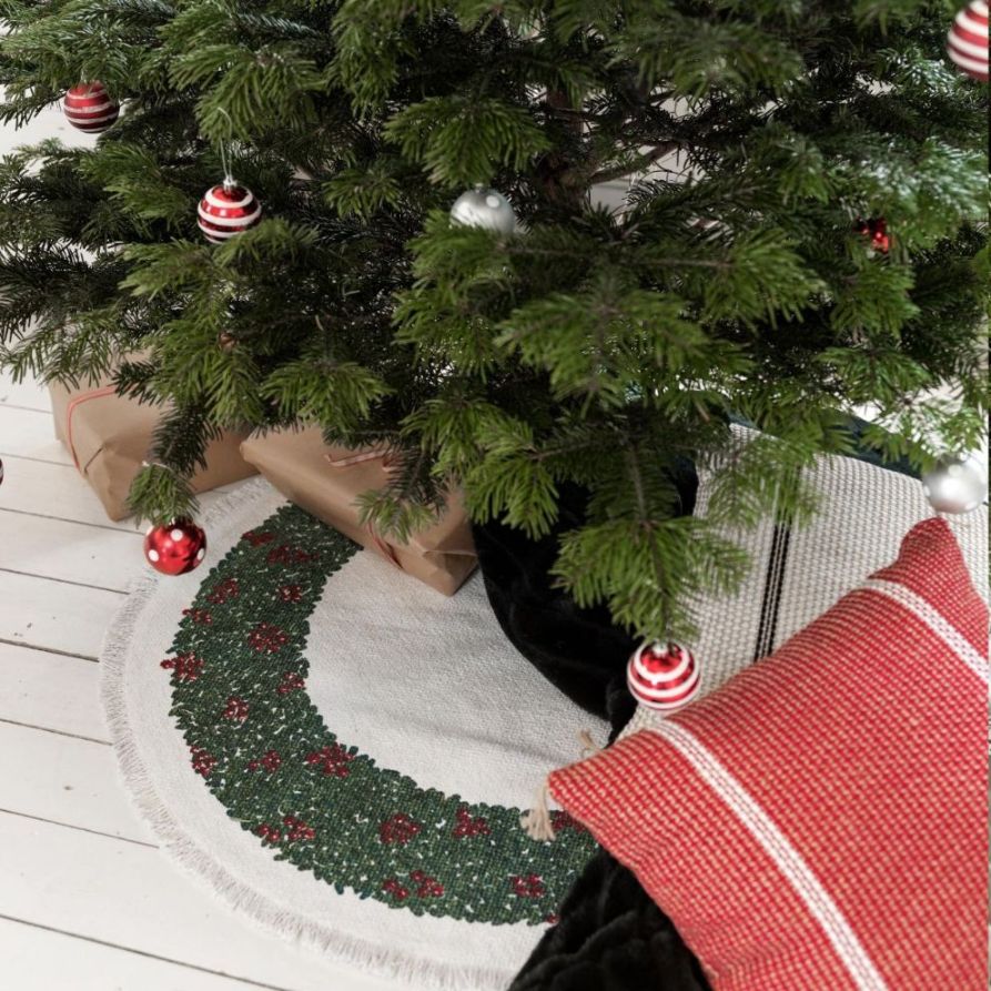 Lingonkrans en rund julgransmatta i 100% bomull i vitt med en grön lingonkrans från Noble house, diameter 95 cm.