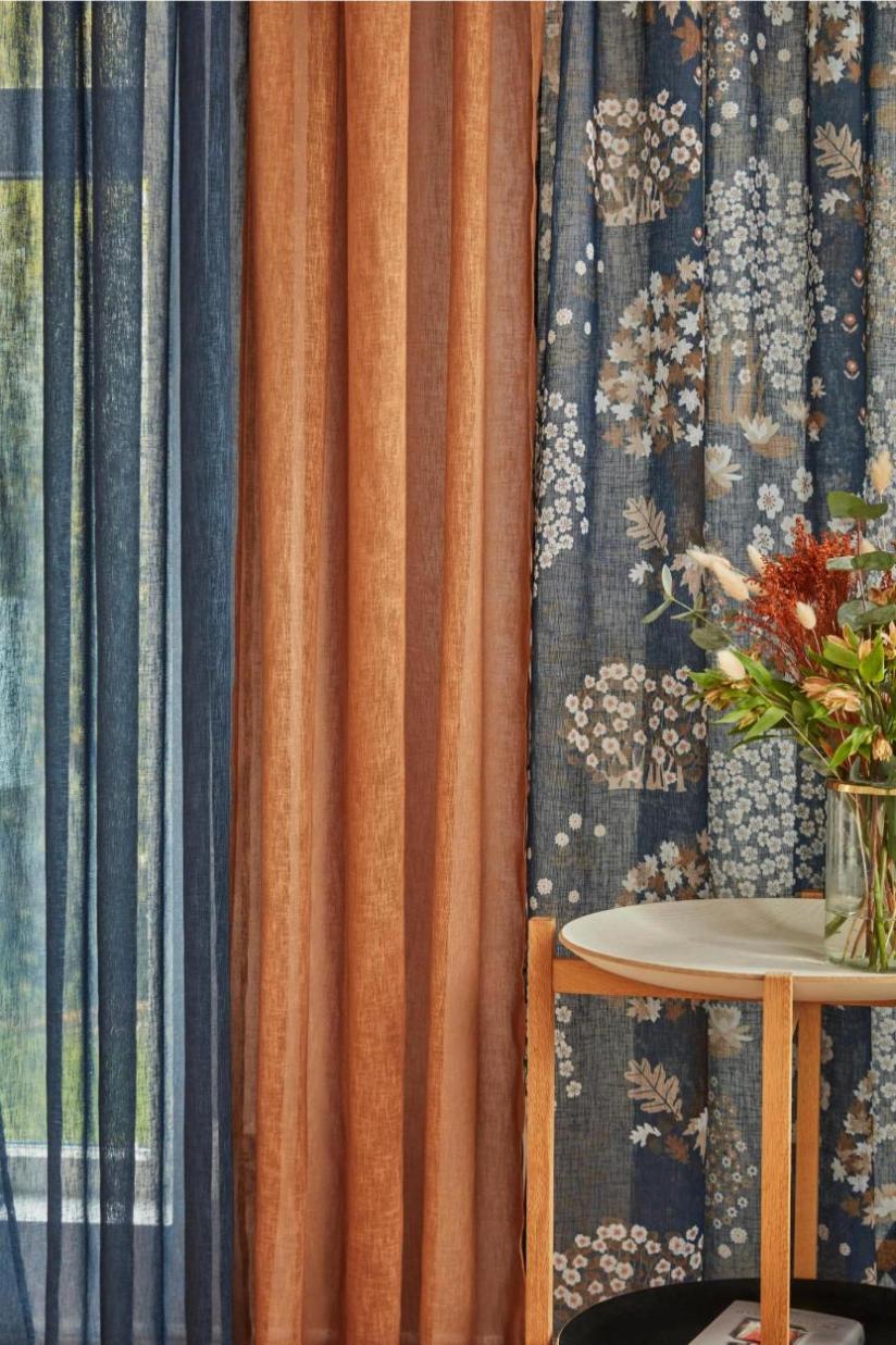 Noble house Saga LN Autumn ett luftigt blått gardinset med små blommor och gråa, bruna och beiga blad och multiband