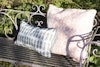 Drällduk rosa/vit och "Berså" tyg i grått av Stig Lindberg sydda som kuddfodral. Fina på en rostig trädgårdsbänk i järn.